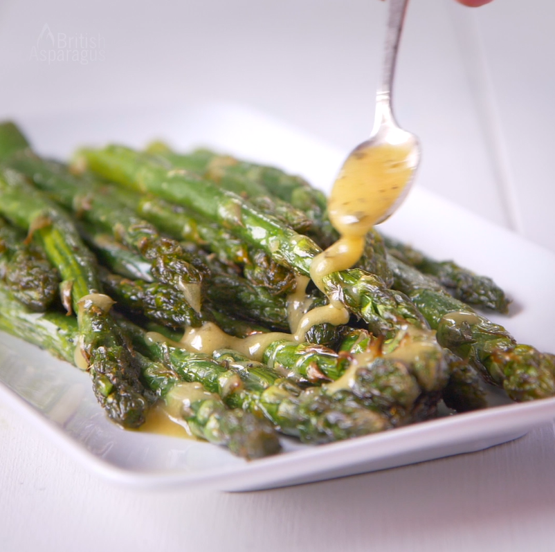 Roasted asparagus having a yellow sauce spooned onto it